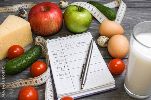 Notebook with table. Fat. Fruits, eggs, yoghurt and measuring tape on a gray background. Ketogenic diet, healthly food. Close up. Diet plan.