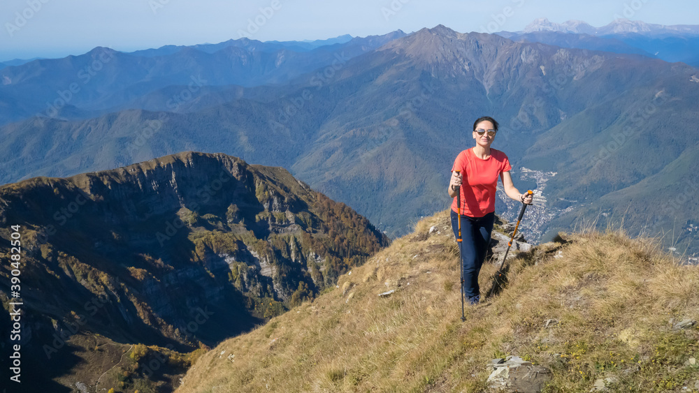 Woman hiker goes hiking, stands on top of mountain and looks at autumn nature mountains landscape in sunny weather. Outdoor activities. Copy space