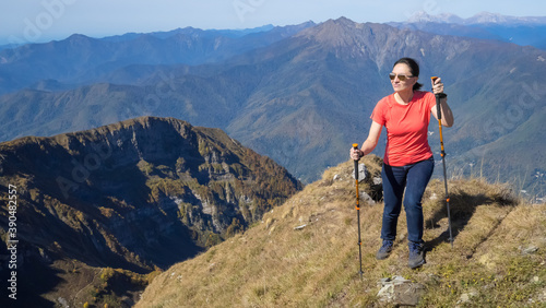 Woman hiker goes hiking, stands on top of mountain and looks at autumn nature mountains landscape in sunny weather. Outdoor activities. Copy space