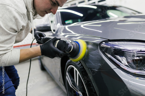 Car detailing - Worker with orbital polisher in auto repair shop.