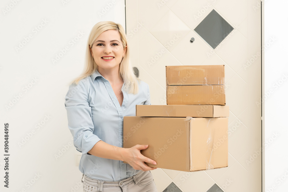 Attractive young woman enjoying a hearty laugh as she holds an cardboard box with packaging in her hands in her living room Attractive young woman enjoying a hearty laugh as she holds an cardboard box with packaging in her hands in her living room