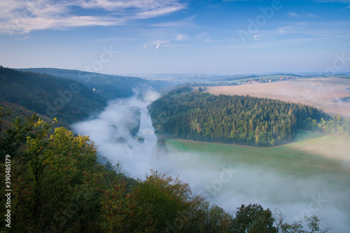 fogg over the morning cold river, beautiful view point to the valley with forest and fields, czech republic