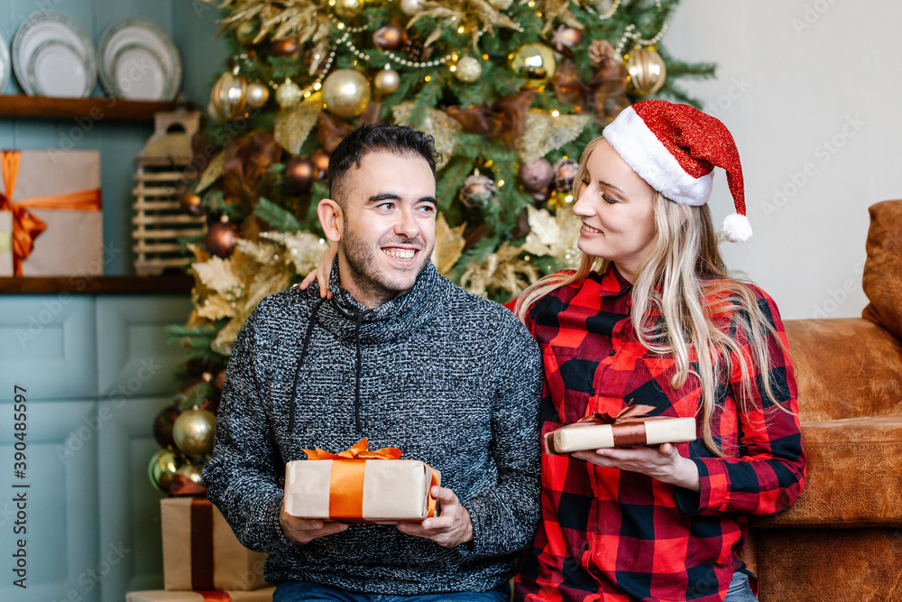 couple exchanging with Christmas presents at home.
