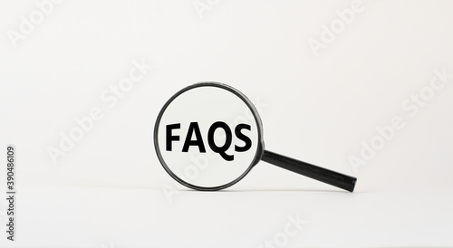 Magnifying glass with text 'FAQS' on beautiful white background. Business concept, copy space.