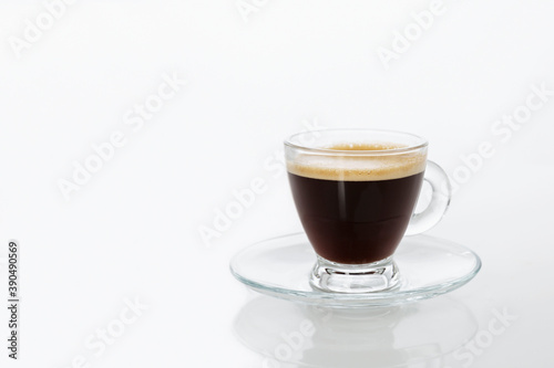 Transparent cup of espresso on a white background. Space for text.