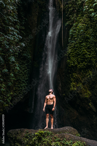 A man of athletic build at the waterfall. A man travels the world. Man at the waterfall. Travel to Bali Indonesia. A person travels through picturesque places. Lone traveler. Copy space