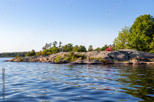 Two empty red chairs on the rocky shoreline of Georgian Bay, Ontario, canada