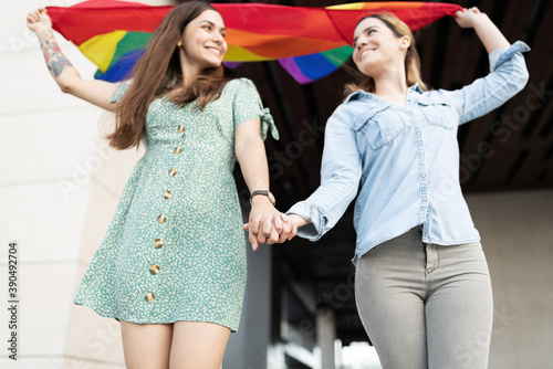 Lesbian partners holding hands with a gay flag