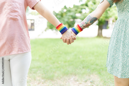 Women friends holding hands with rainbow wristbands