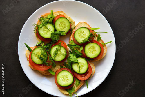 Diet sandwiches with greens, cucumber and tomato on a white plate