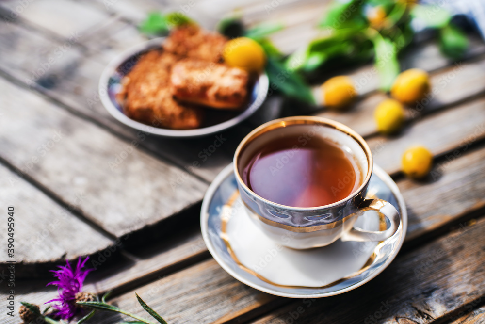 Cup of hot tea and cookies, bowl with yellow plums in   on a wooden table. Coziness and comfort in the house. Thanksgiving day.