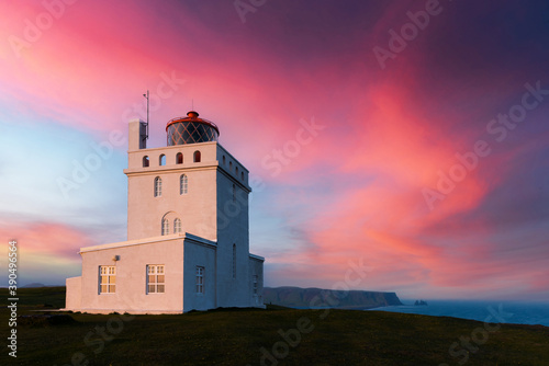 Incredible evening view of Dyrholaey Lighthouse at Cape Dyrholaey, south coast of Iceland. Great purple sunset glowing on background. Landscape photography