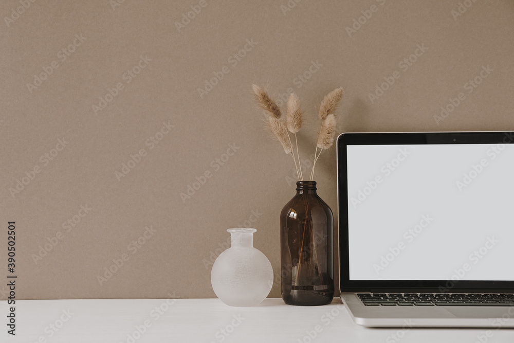 Blank screen laptop. Home office desk table workspace with fluffy plant in bottle on pastel beige background. Copy space mockup blog, website template. Blogger, outsourcing freelancer hero header. - obrazy, fototapety, plakaty 