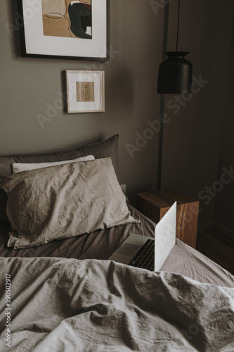 Modern interior design concept, Hygge styled bedroom with grey washed linen bedclothes, pillows, laptop, wooden nightstand, hanging lamp, Minimalistic nordic living room,