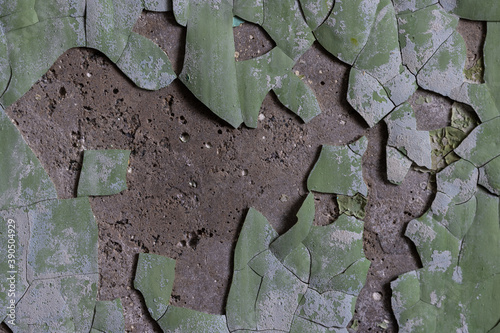 Peeling paint on the wall. Old concrete wall with cracked flaking paint. Weathered rough painted surface with patterns of cracks and peeling. Grunge texture for background and design. High resolution.