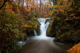 the waters of the waterfall at furnace at long exposure, flowing down the rocky cliff. the autumn colours in the trees