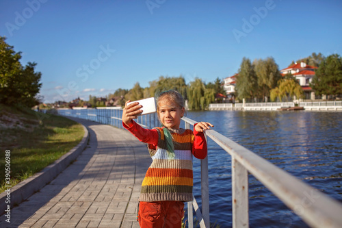 Stylish tween girl with mobile phone walking in the street, kid and gadgets