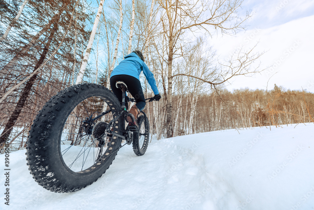 Fat bike biking girl riding on snow trail path in winter. Outdoor sport in nature landscape. Fat bike biking girl riding on snow trail path in winter. Outdoor sport in nature landscape.