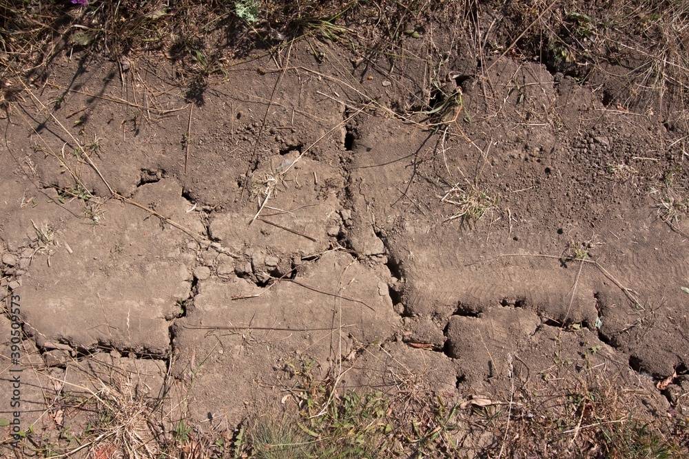 detail of countryside dirt road with deep cracks in soil, dry surface during a drought, hot sunny summer day without rain, human impact on nature detail of countryside dirt road with deep cracks in soil, dry surface during a drought, hot sunny summer day without rain, human impact on nature