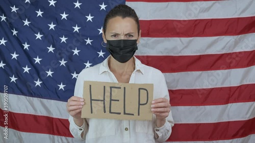 Bankrupt businesswoman. A need bunkrupt woman in medical mask asked for help during quarantine time against of American flag. photo