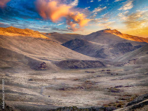 Vast dramatic landscape with a winding dirt road and a Side by Side atv off in the distance. photo