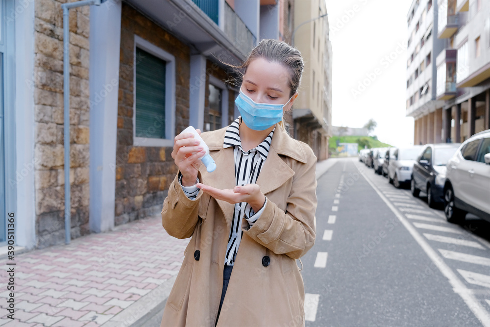 Fototapeta premium Business female in face protective mask on urban street. Health protection and social distance concept. Lockdown quarantine time. Hand hygiene.