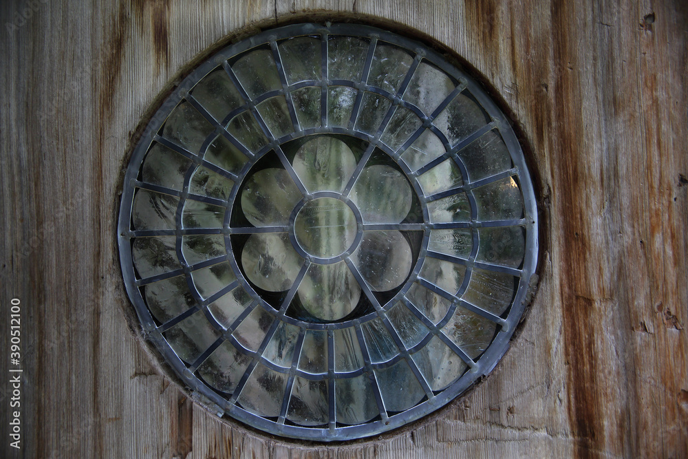 lead and glass round window set in an old wood door