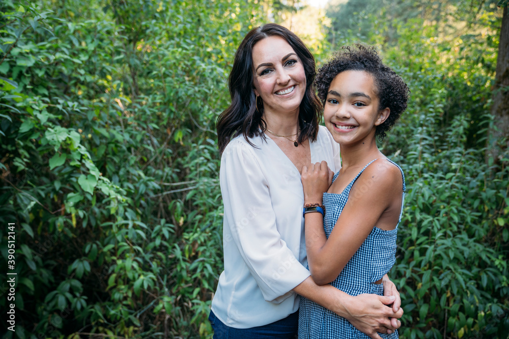 Portrait of mom hugging happy teen daughters outside