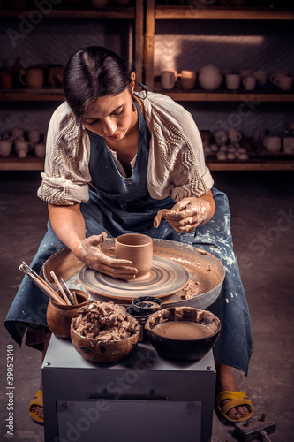 The potter works in the workshop. Hands and a potter's wheel close-up.
