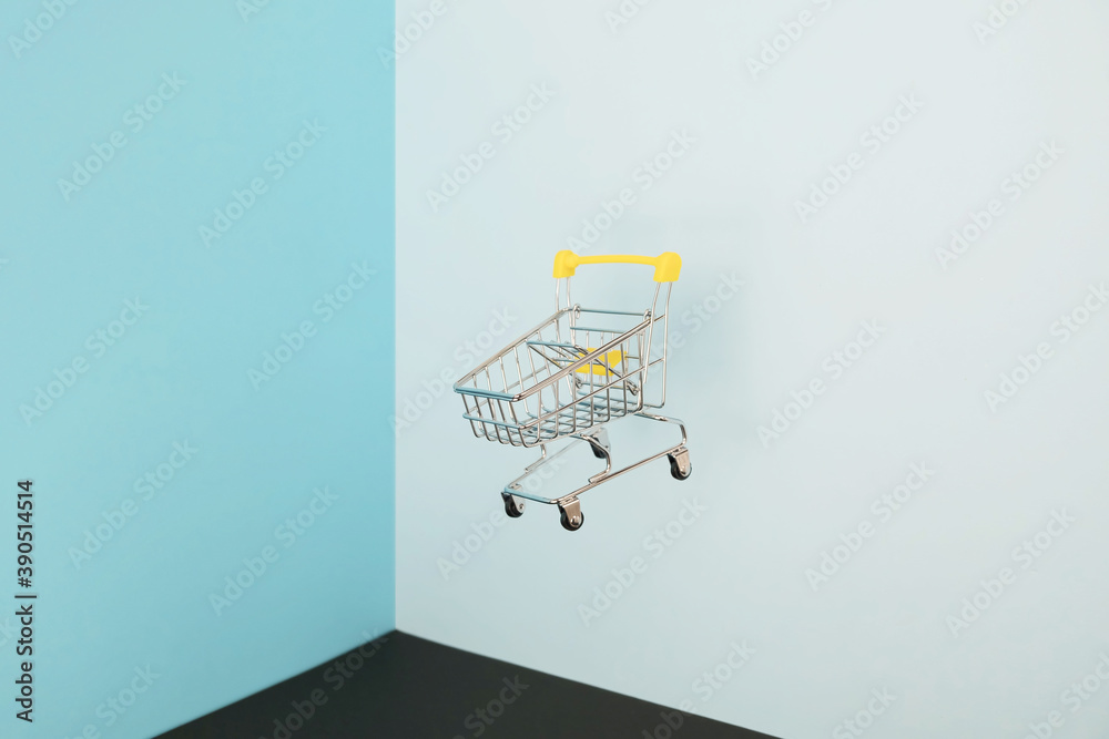 Levitating shopping cart on blue background. Safe online shopping on quarantine concept. Flying Empty supermarket shopping trolley with copy space