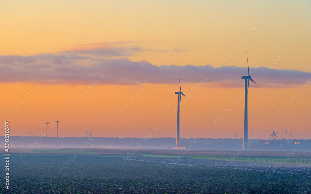 Obraz premium Wind turbine in a yellow sky in bright sunlight at sunrise in an early autumn morning, Almere, Flevoland, The Netherlands, November 5, 2020