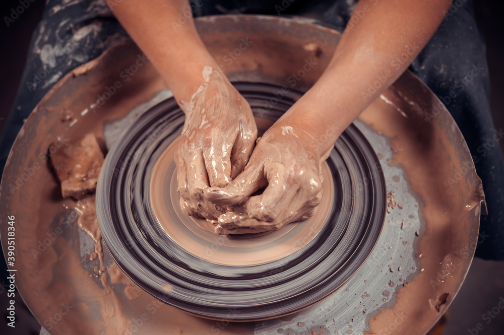 Hands of the master potter and vase of clay on the potter's wheel close-up. Master crock. Twisted potter's wheel.