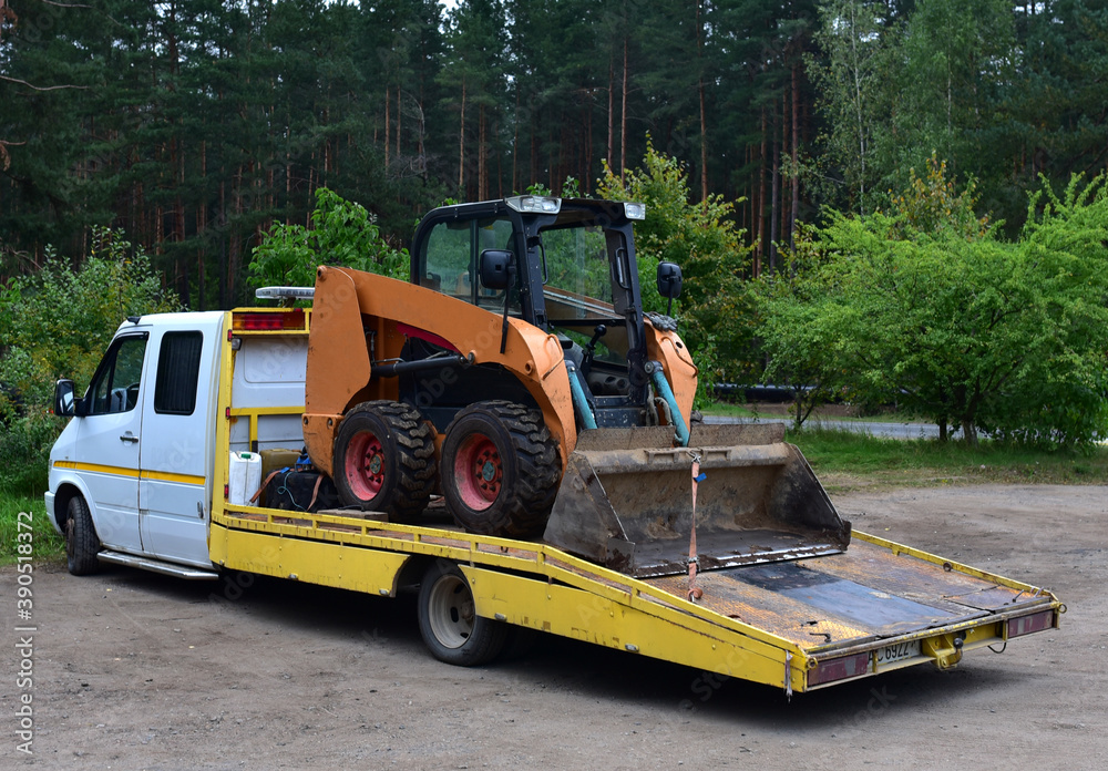 Shipping the Skid Steer Loader on truck. Transporting Сompact construction equipment and heavy machinery.