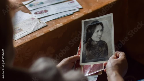 Elderly woman sitting in armchair and browsing old photos