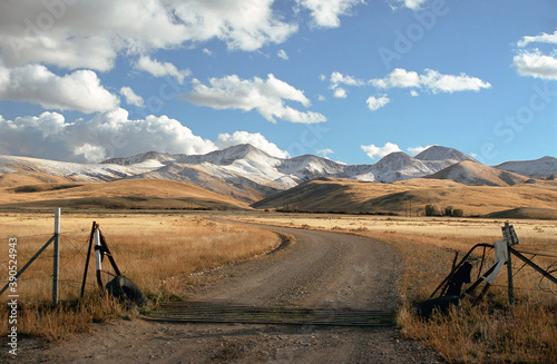 Montana Ranch entrance with road, hills, snow, and sky. photo