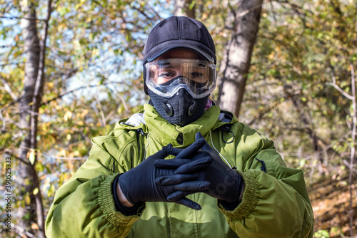 A woman wearing a respirator mask and protective glasses in the forest at COVID-19 period. © Sergei