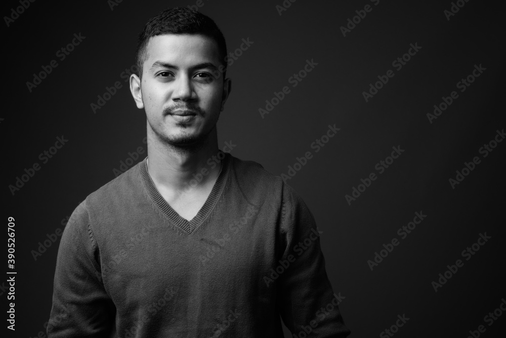 Young multi ethnic Asian man against gray background