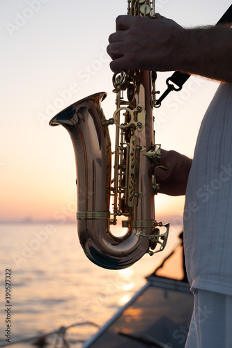 Jazz musician performing on saxophone by the seaside at sunset