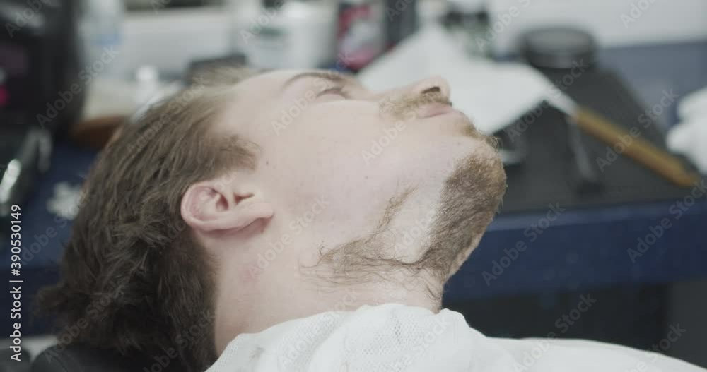 Barbershop. Styling beard and moustache with a razor and small scissors. Caucasian male model. Hair salon in background Barbershop. Styling beard and moustache with a razor and small scissors. Caucasian male model. Hair salon in background