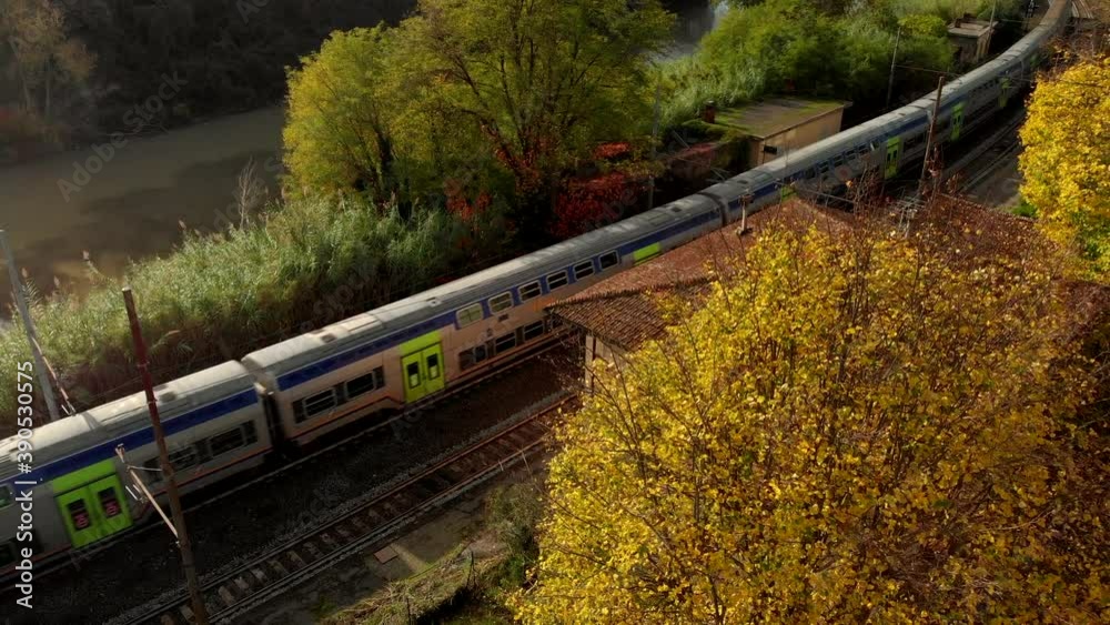 Aerial view of a train passes through an abandoned station in autumn. Transportation, travel and tourism concept. Drone shot