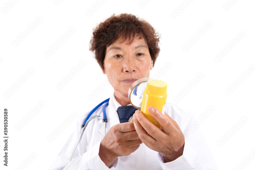Chinese old doctor is looking at medicine bottle with magnifying glass in front of white background Chinese old doctor is looking at medicine bottle with magnifying glass in front of white background