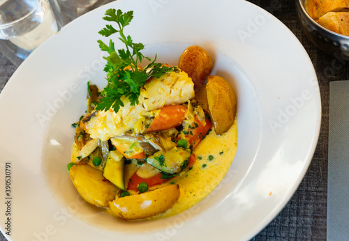 Spanish style hake steak served with baked vegetable and creamy sauce. Traditional French cuisine