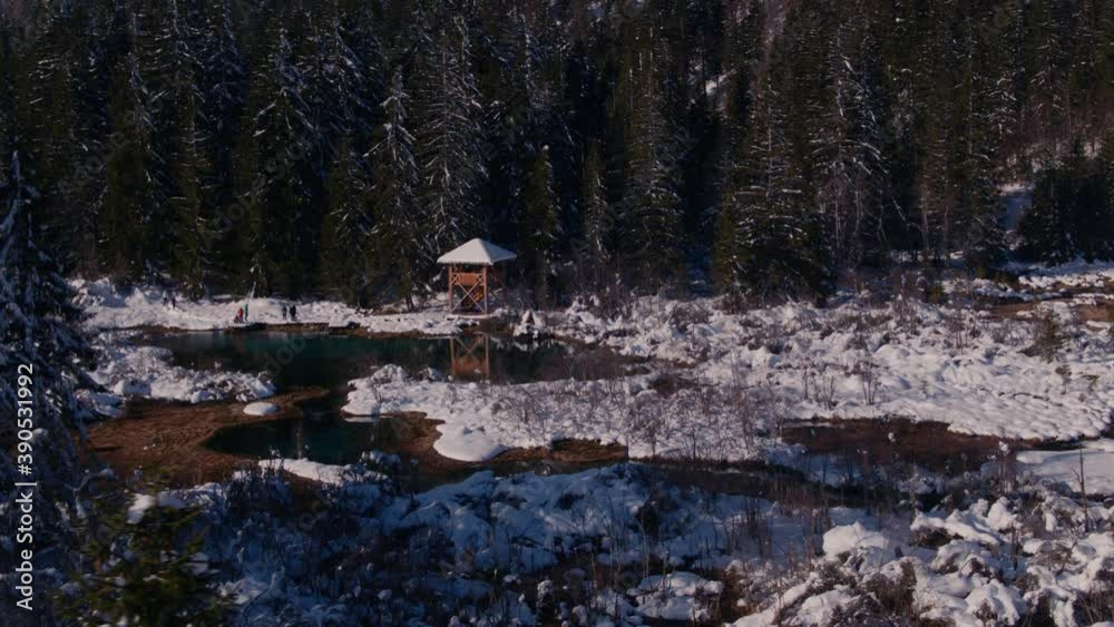 Revealing drone shot of observation tower and magical bright green colour lake with idyllic winter scene - Zelenci in Slovenia. Revealing drone shot of observation tower and magical bright green colour lake with idyllic winter scene - Zelenci in Slovenia.