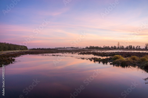 Early sunrise reflects subtle tones on the still surface of water in the foreground.