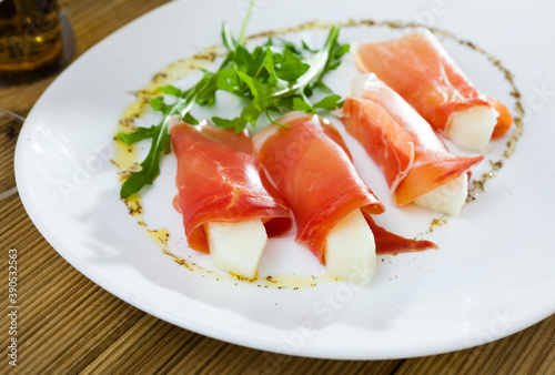 Thin slices of jamon served with melon and arugula - national Spanish snack
