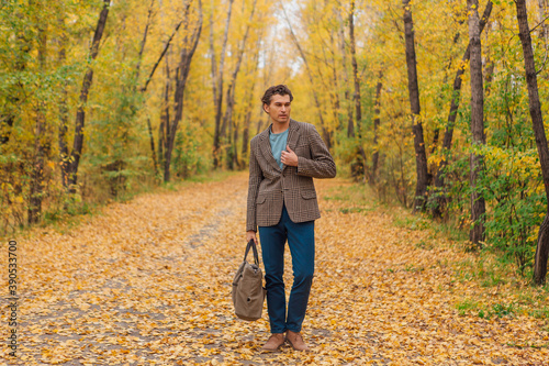 Tall handsome man with a bag on the autumn alley © Smile