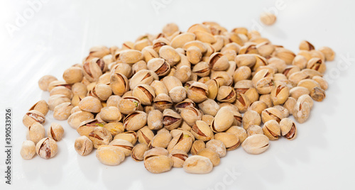 Pile of unshelled roasted pistachios on white surface. Concept of healthy and nutritious food