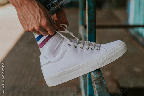 Photos Man fixing shoelaces on white sneaker