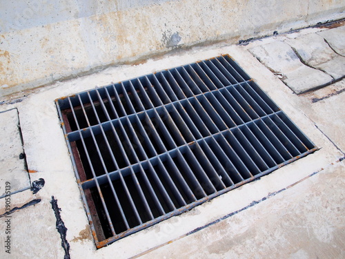 Metal grid on the Main Hole. Grates to prevent debris or people from falling into the sewer on the street. On a concrete floor background with a copy area. Close focus and select an object