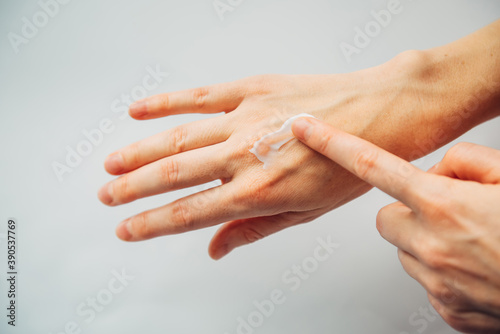 Close up female hands applying moisturizing cosmetic lotion, on white background. Woman's adult hands, apply nutrient cream. Skincare, beauty treatment concept. Repair damaged dry skin.